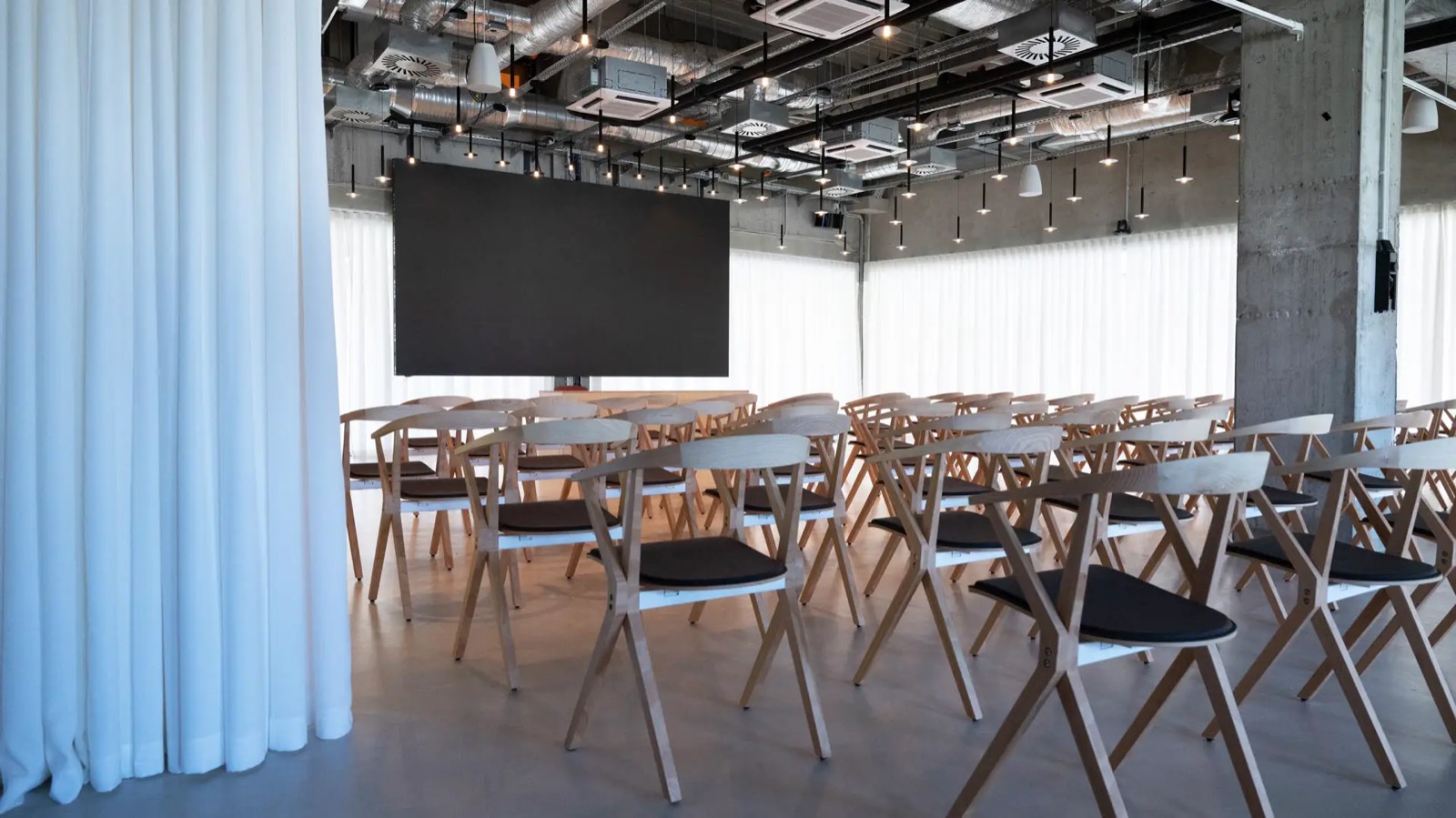 Peron Hall at Ložionica, Belgrade, the DECODE Summit venue: light oak chairs facing the stage and LED screen beneath the restored roundhouse’s concrete ceiling